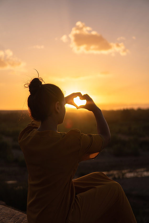 Woman at Sunset Creating Heart Shape With Her Hands